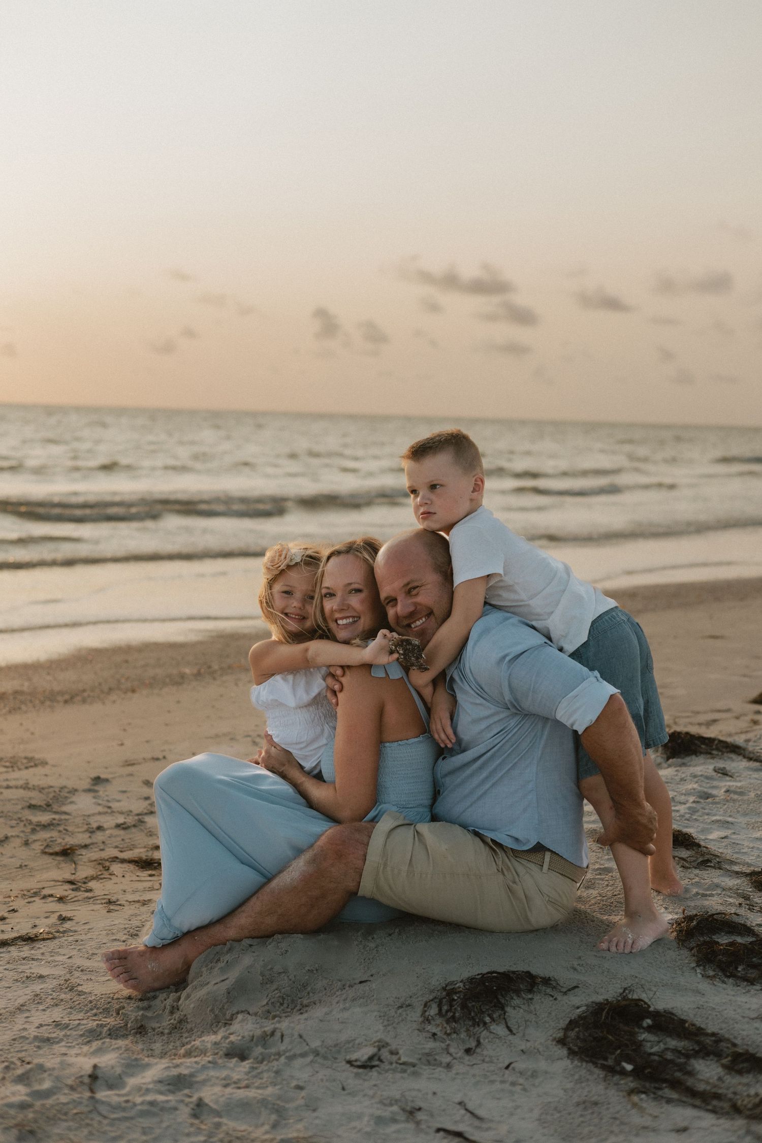 Group lounging together on sandy beach at sunset.