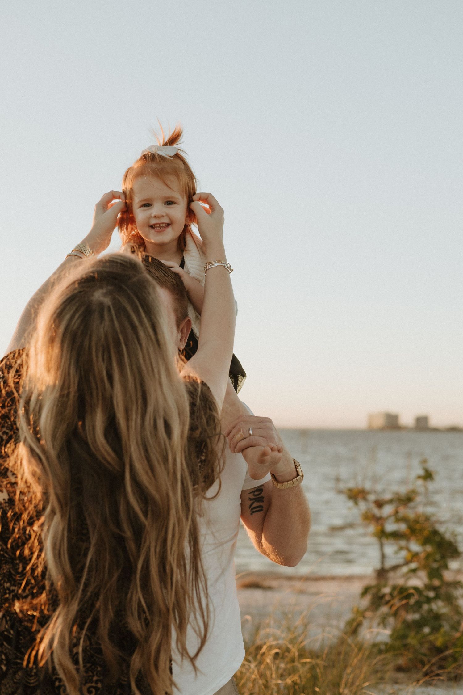 Joyful outdoor family moment captured in golden sunlight by the water.
