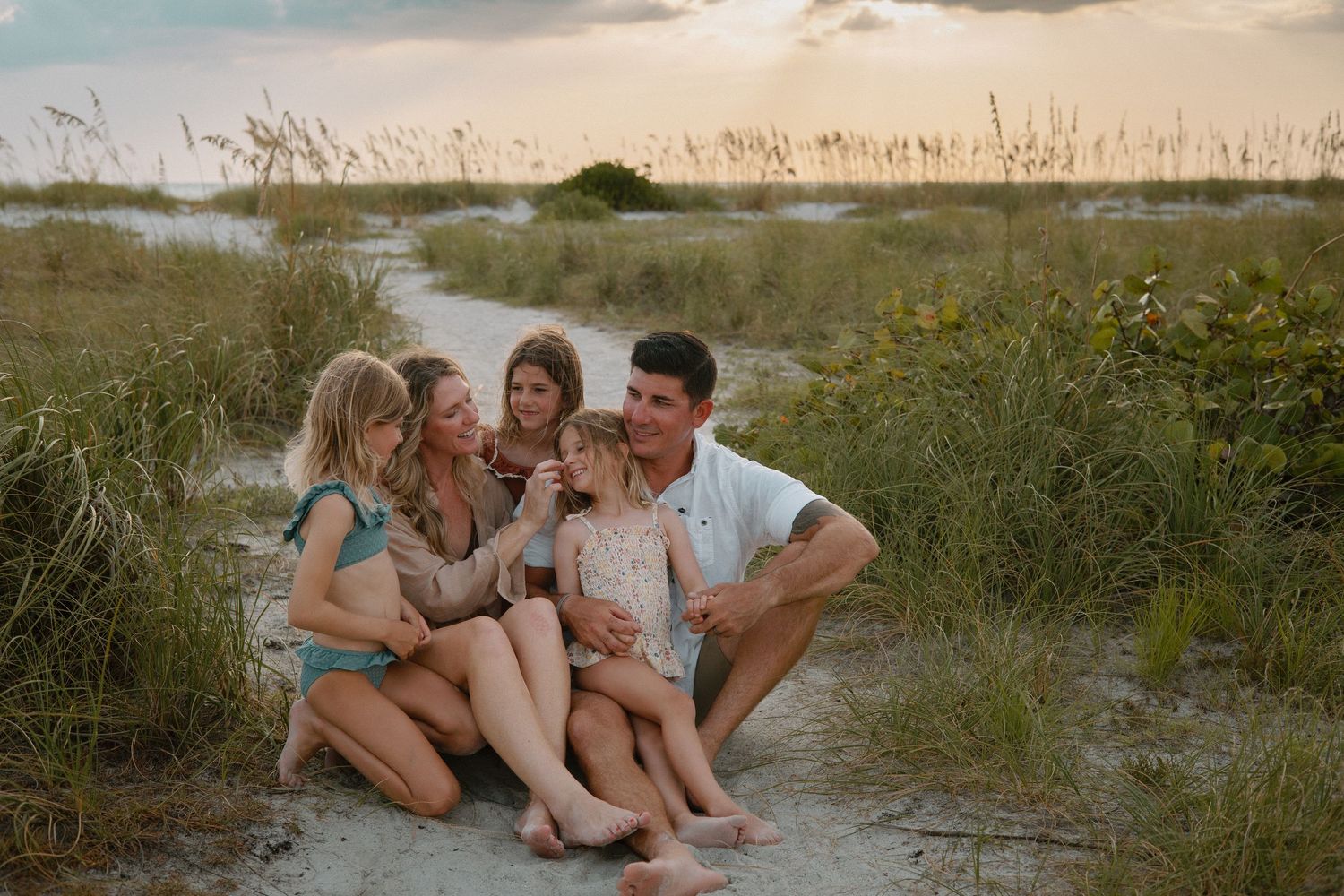 Happy family relaxing together on sandy beach during sunset.