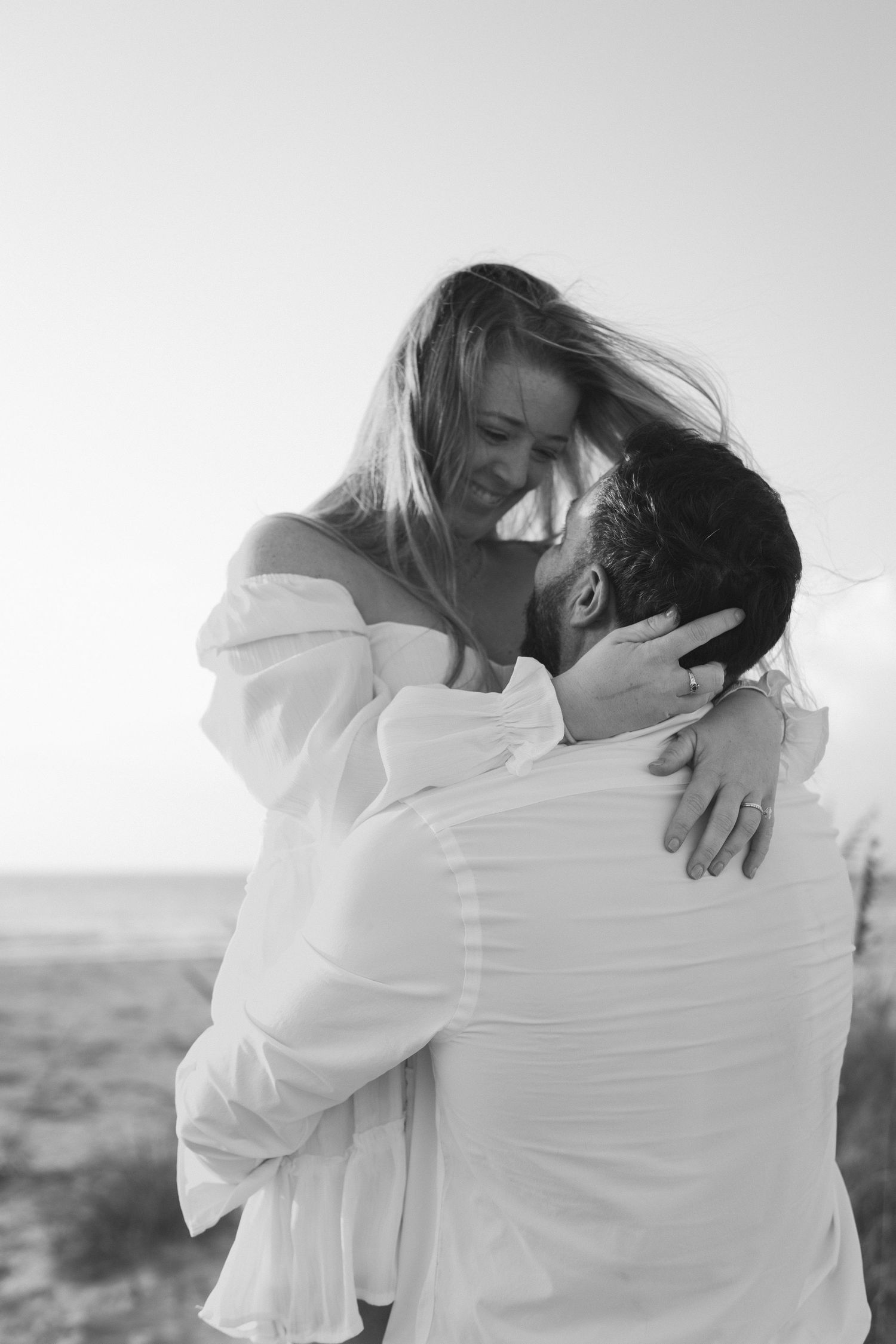 A romantic black and white photo series showing a couple embracing and kissing in an outdoor setting.