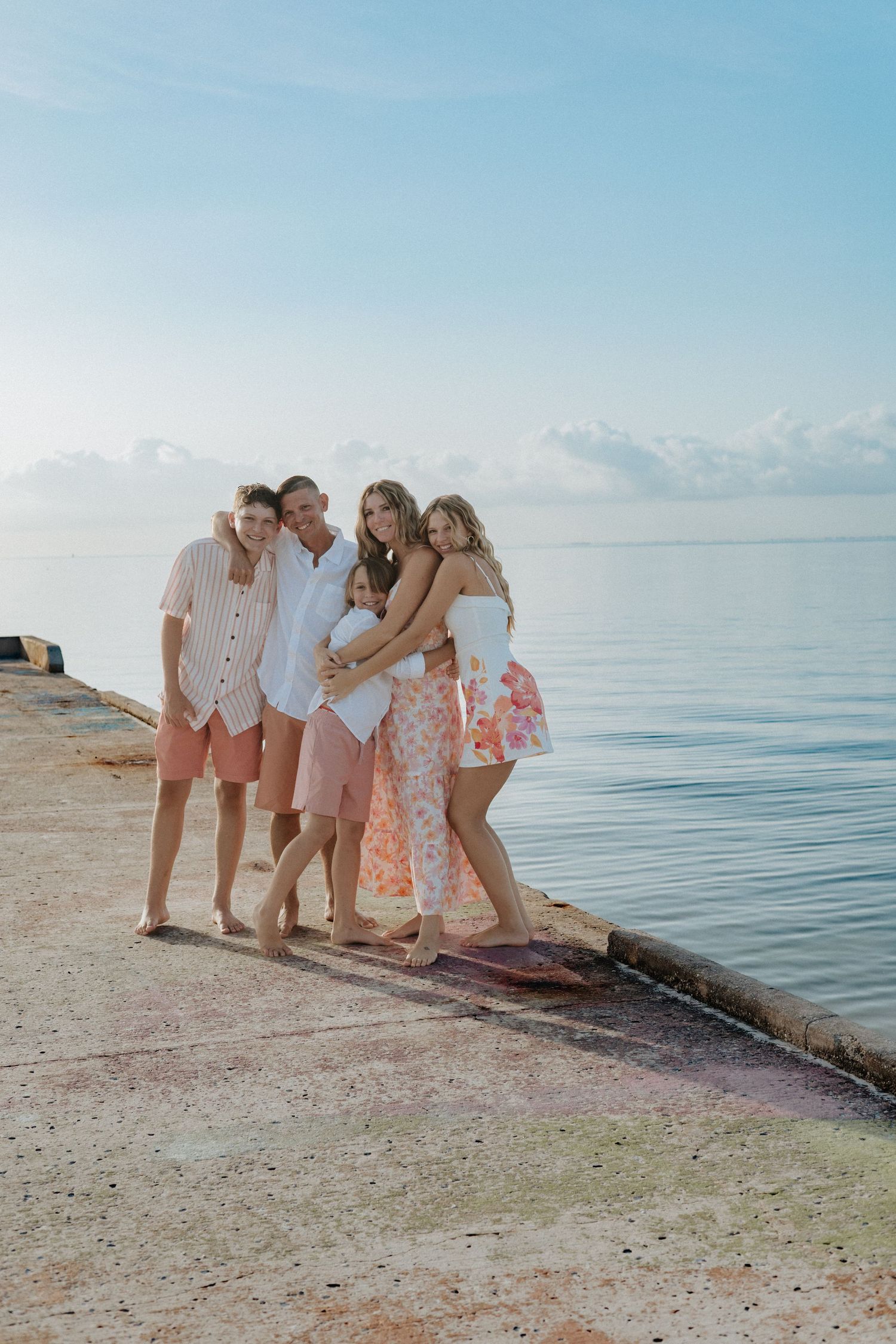 Beach photoshoot with people in coordinated pink and white outfits.
