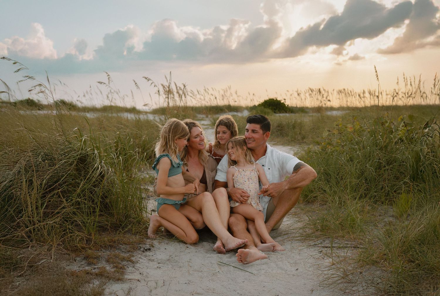 Family relaxing together in tall grass during golden hour.