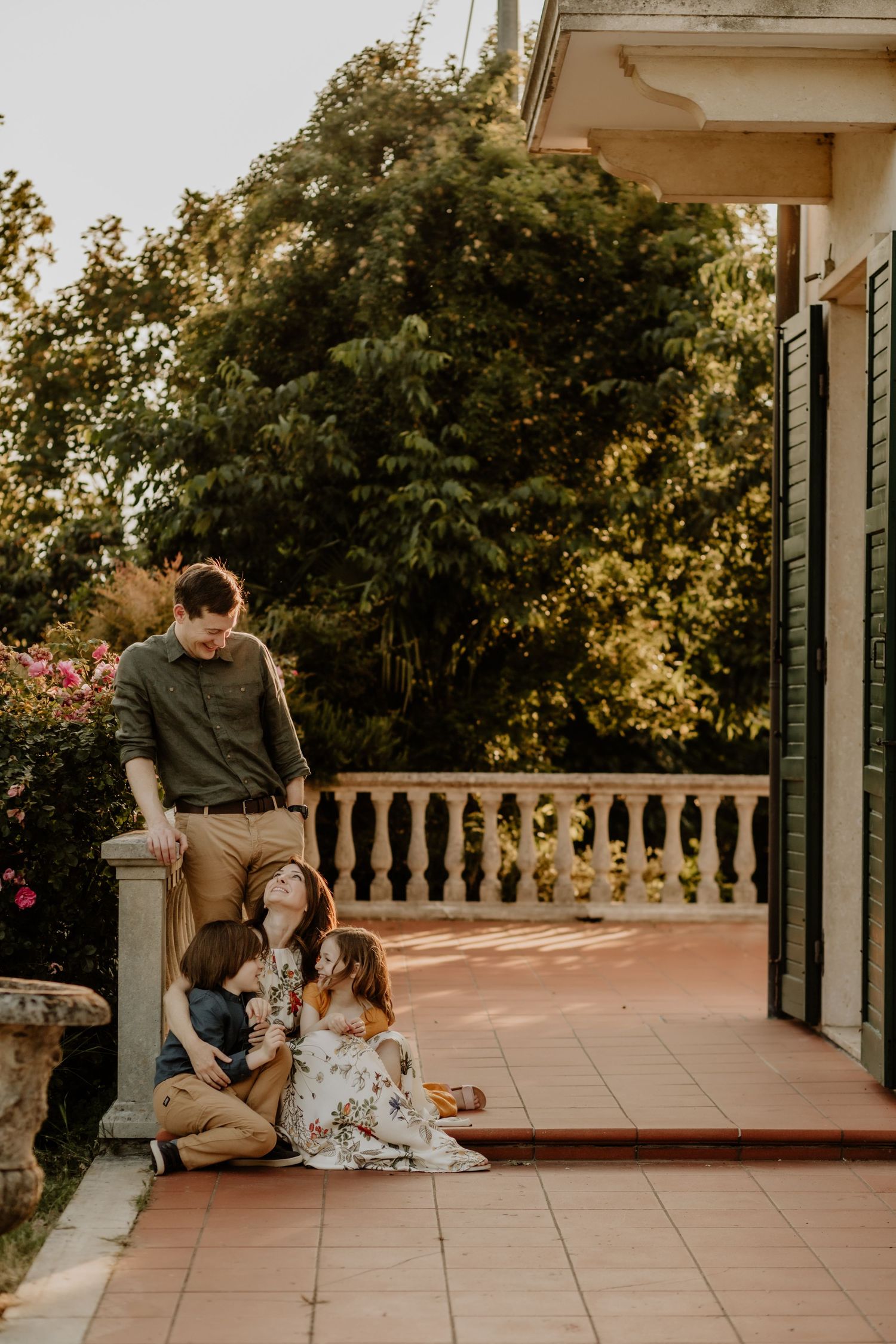 Family gathering on an elegant tiled porch with lush greenery.