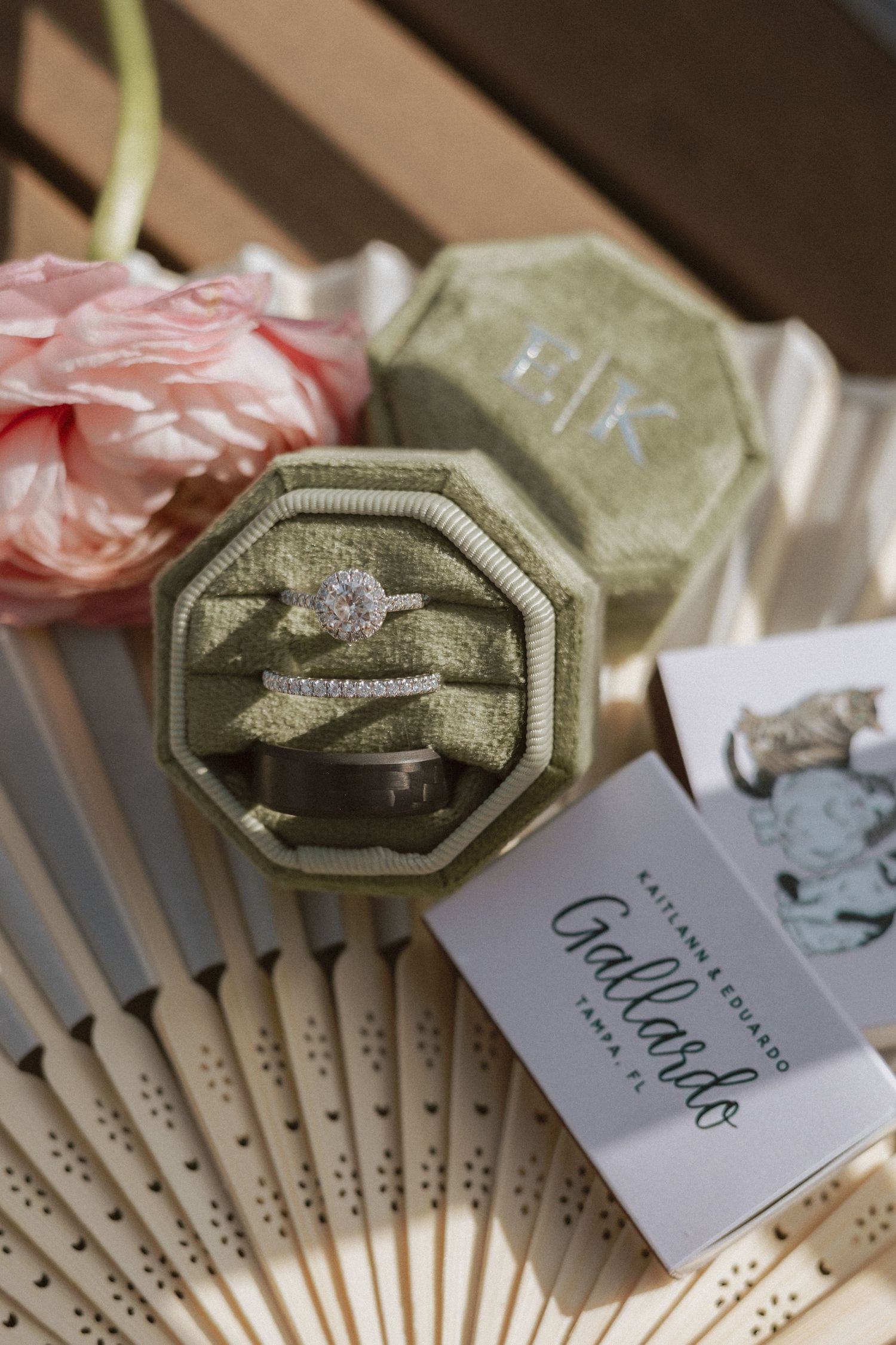 Wedding favors featuring elegant fans with name tags and ring details in green and pink tones.