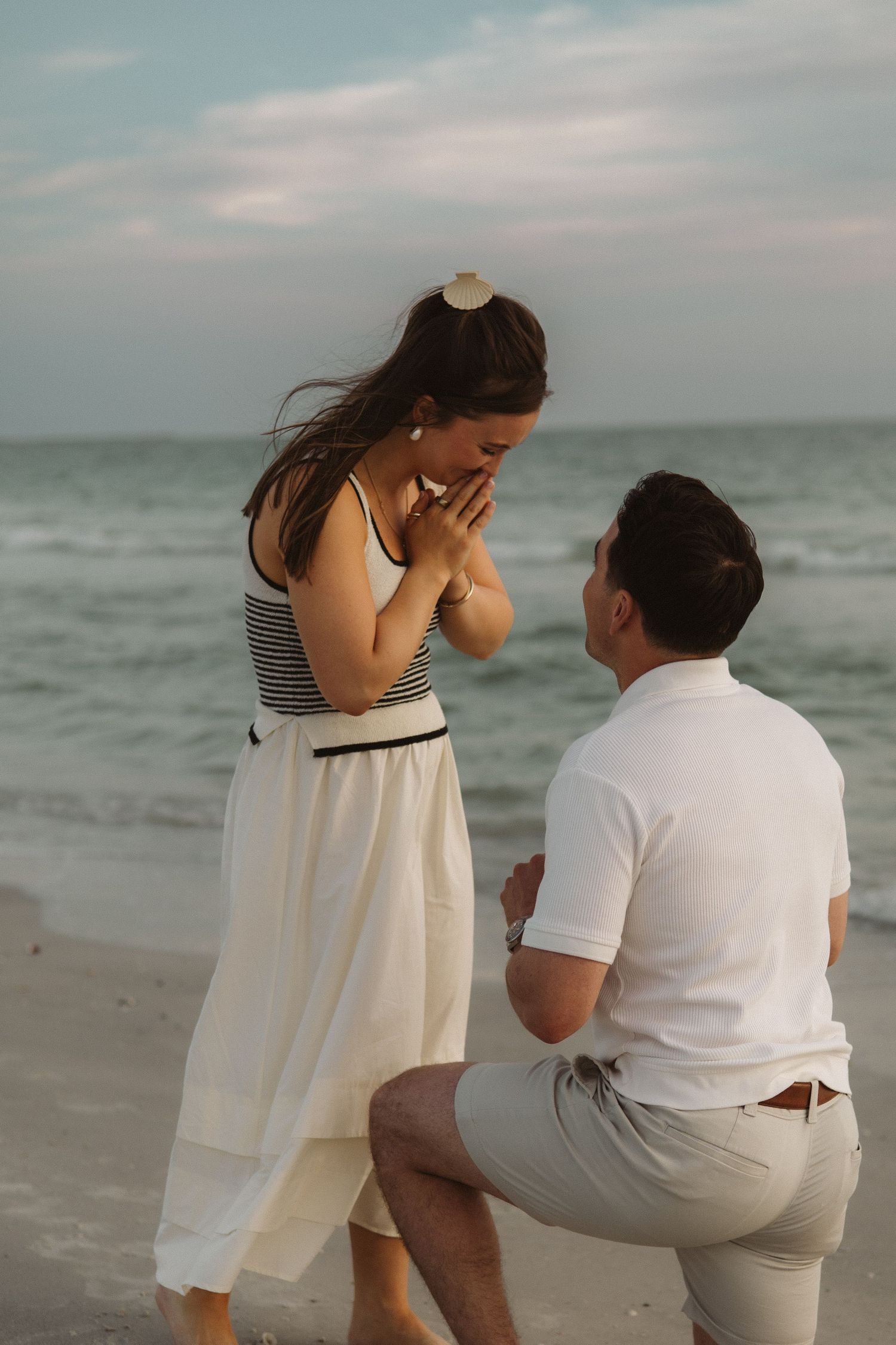 A romantic beach proposal sequence showing a couple during a sunset engagement moment by the ocean.