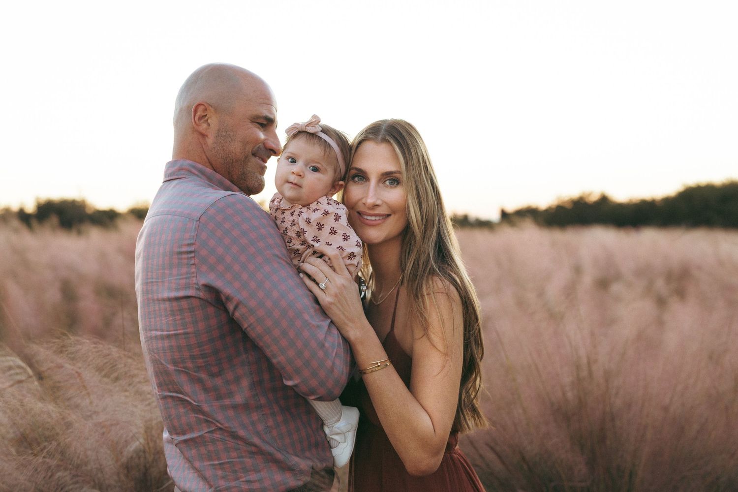 A couple embraces in a field of tall grass during sunset creating a romantic silhouette.