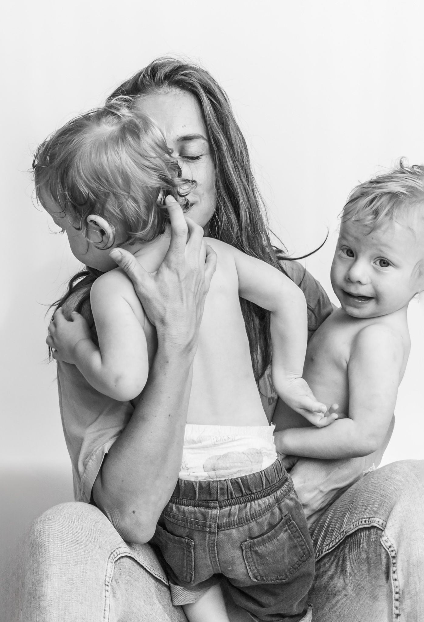 Black and white sequence of images showing a parent and child sharing affectionate hugs and kisses against white background.