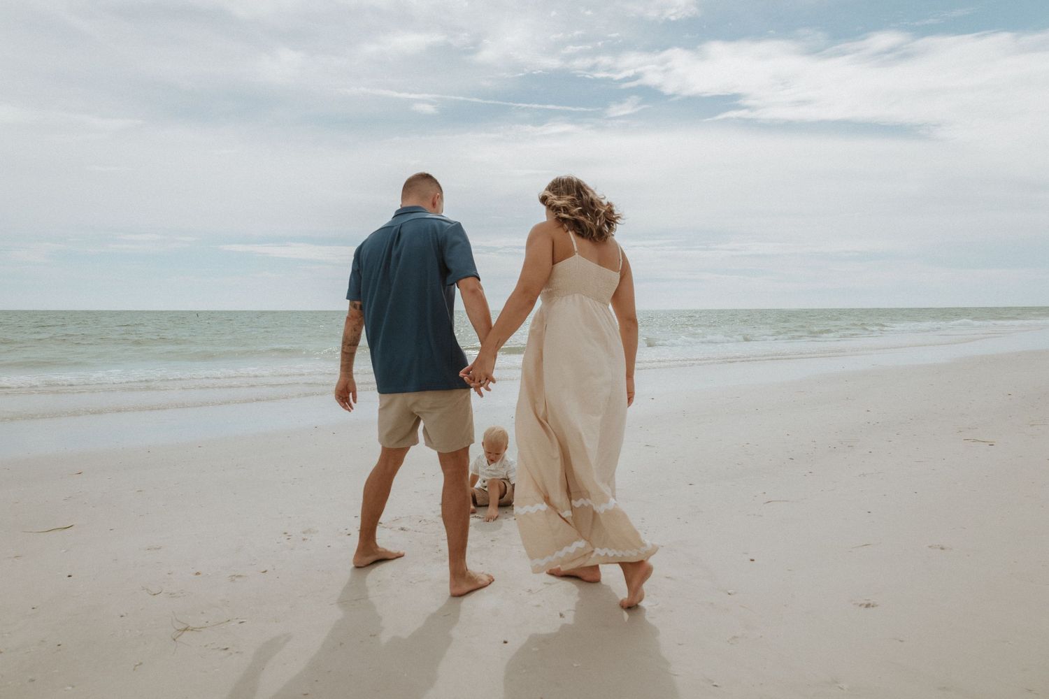 Candid moment of people walking along a serene beach at dusk.