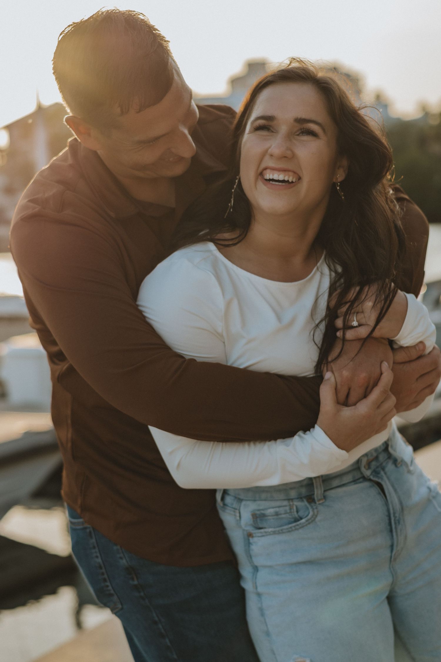 Couple embracing and laughing during golden hour photoshoot.