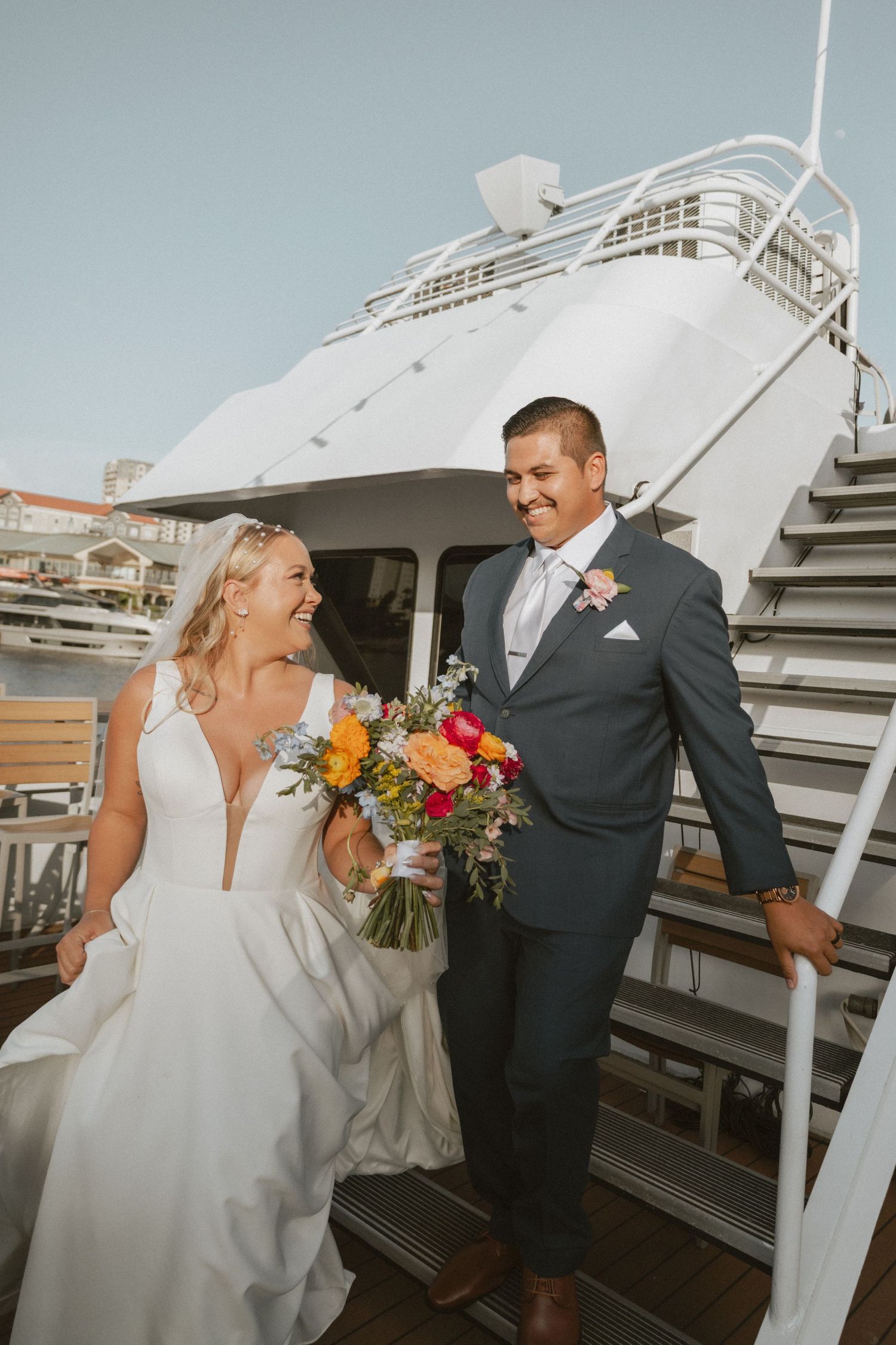 Wedding couple sharing romantic moments on boat dock with white yacht backdrop.