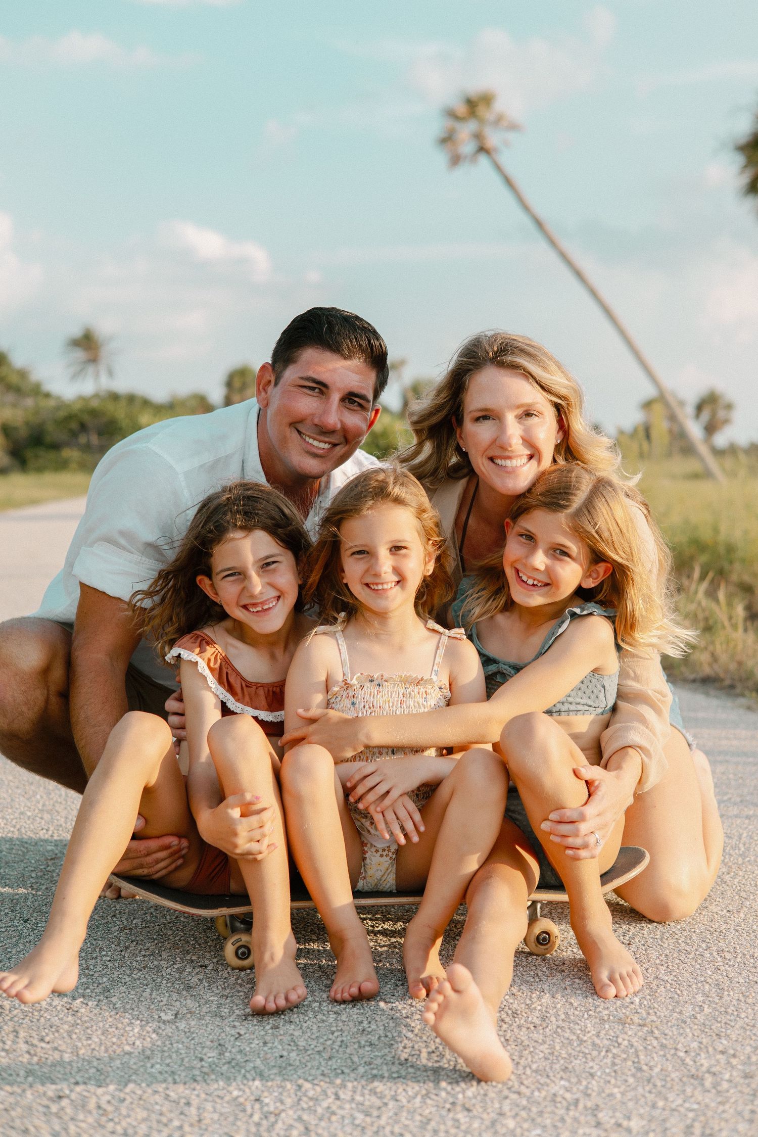 Candid beach family photo sequence with everyone sitting close together on the sandy shore.