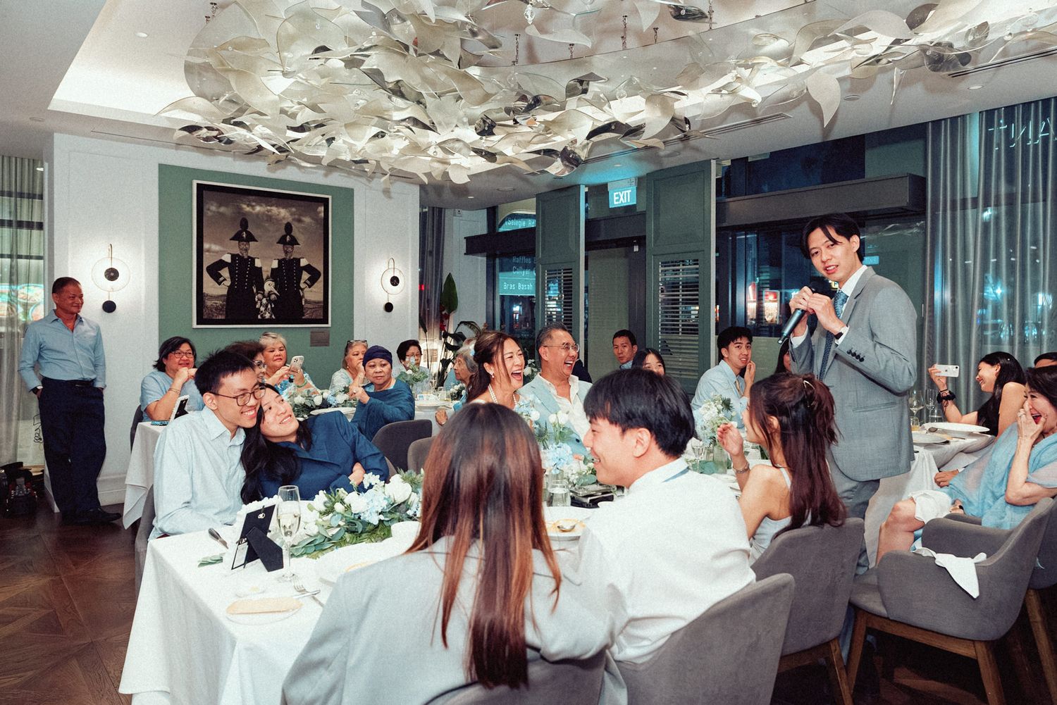 Panoramic view of a banquet hall with white table settings and decorative ceiling installations.