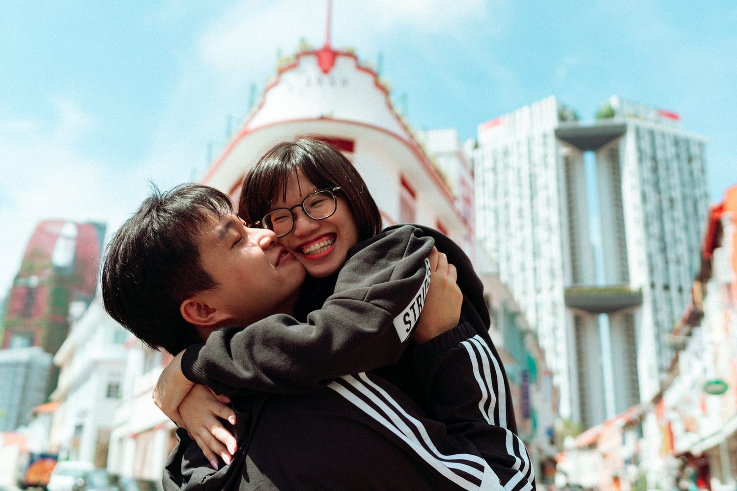 A series of black and white photos showing a couple embracing and sharing intimate moments against a city backdrop.