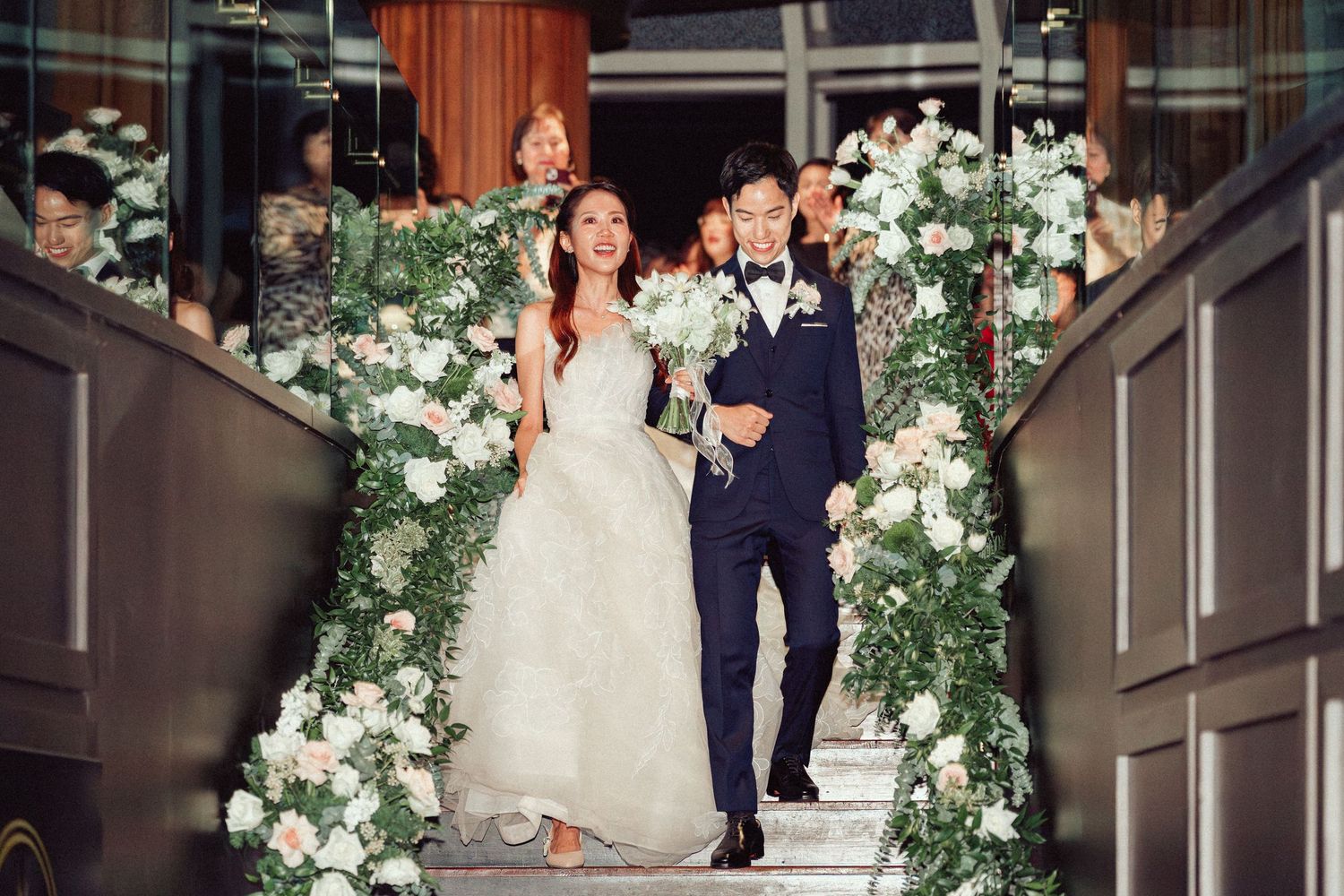 Wedding ceremony setup with white floral arches and decorations in an elegant indoor venue.