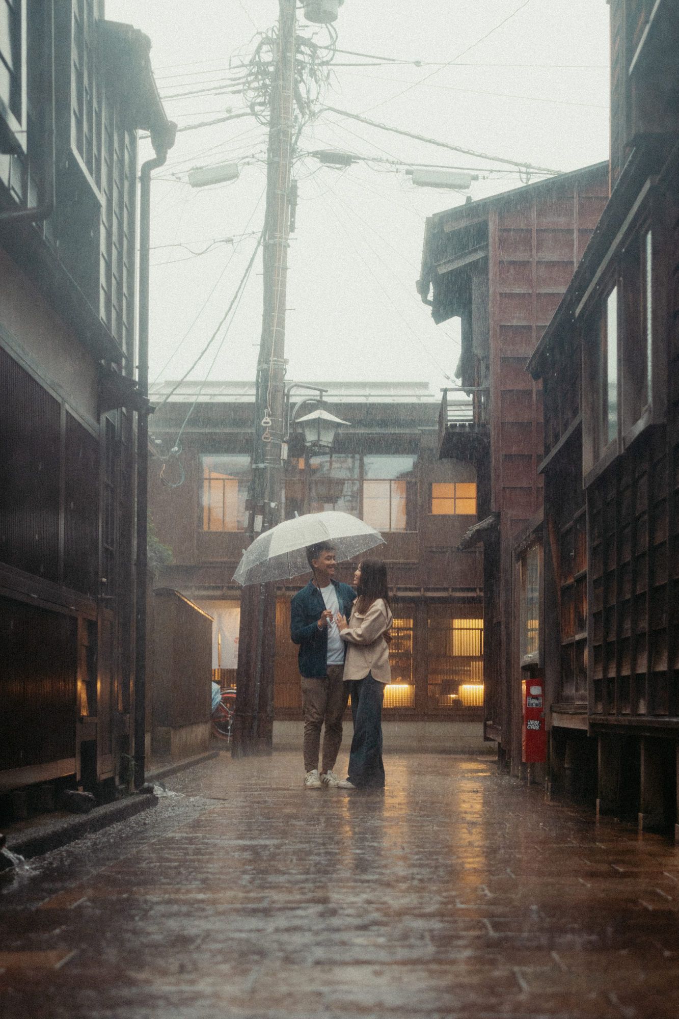 Rain falls on a historic Japanese street lined with traditional wooden buildings.