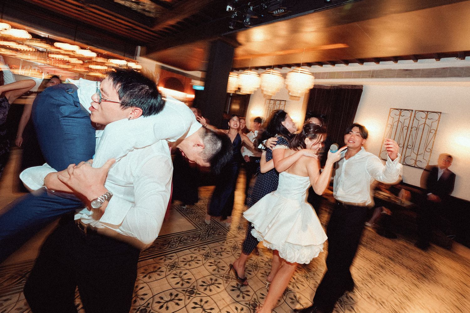 Couples dancing together in a dimly lit ballroom during what appears to be a social dance event or celebration.