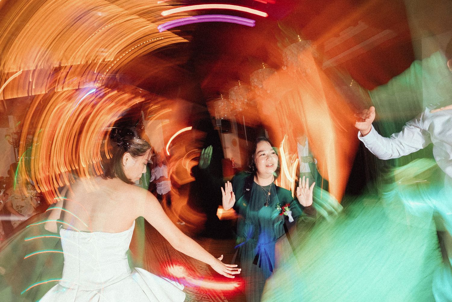 Long exposure photograph shows colorful light trails and motion blur at a dance party or nightclub event.