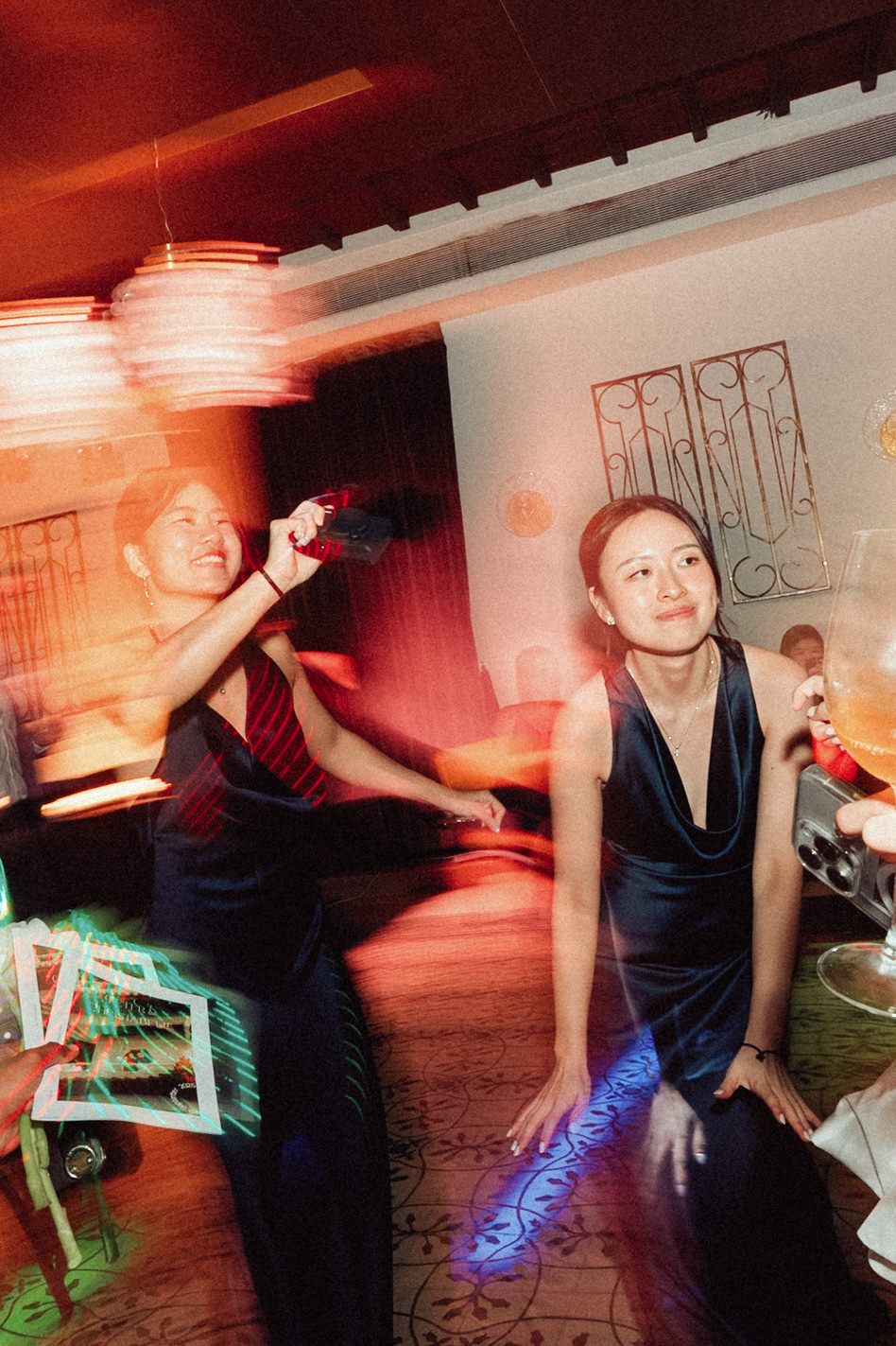 People dancing and socializing at a party with red lighting and neon accents in a casual indoor setting.
