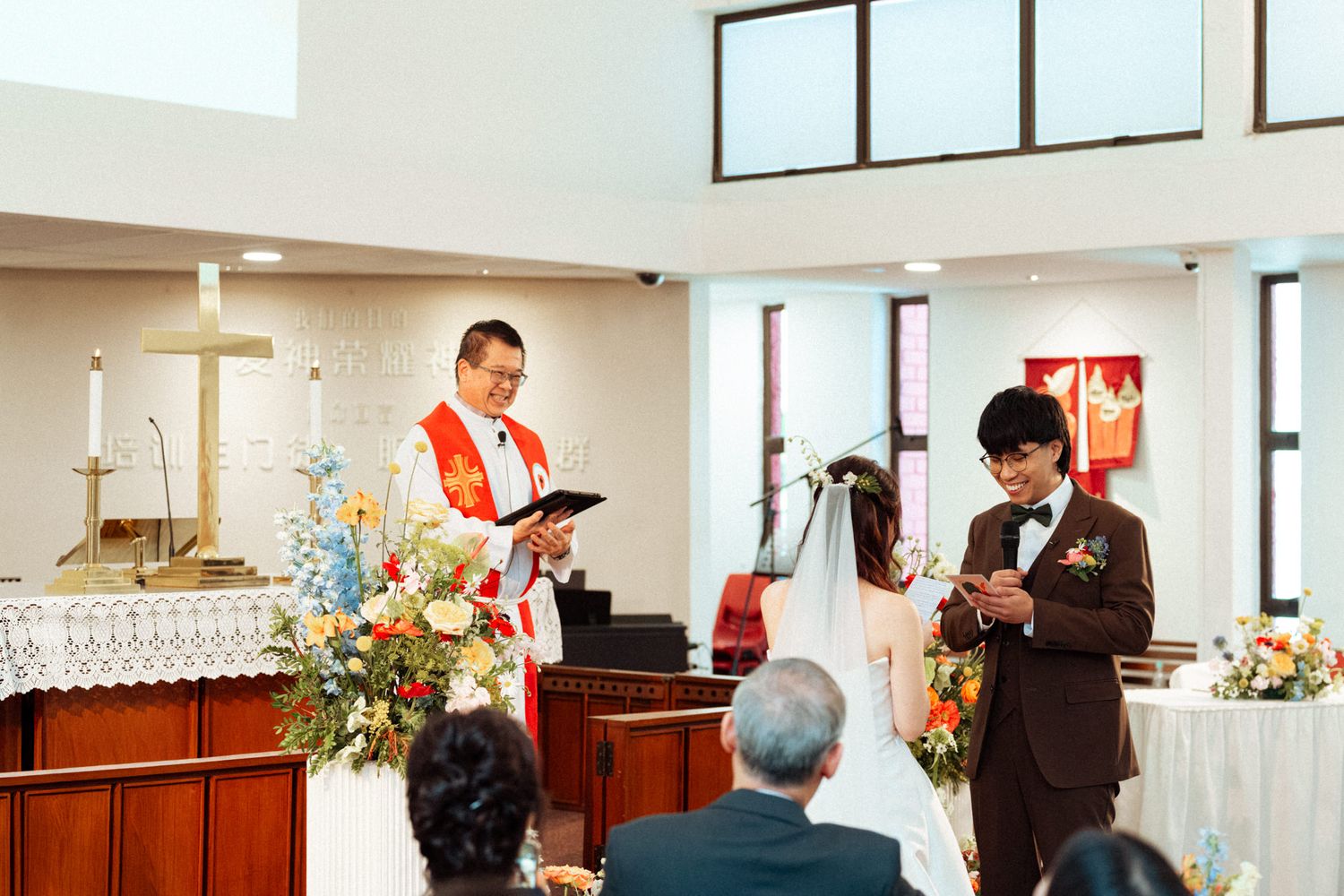 A priest officiates a wedding ceremony in a church as the bride and groom exchange vows at the altar.