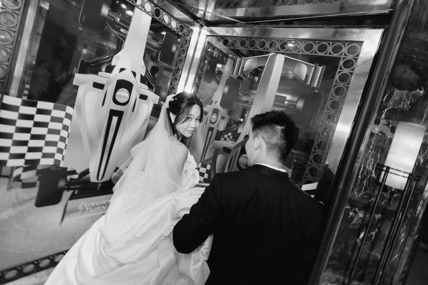 A black and white wedding photo showing a couple at a retro diner with checkerboard decor.