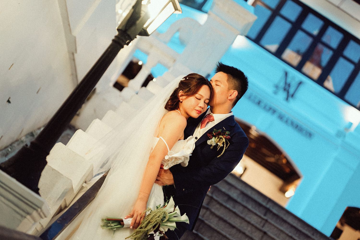 A romantic wedding couple shares intimate moments in front of a bright turquoise wall in a series of candid photos.