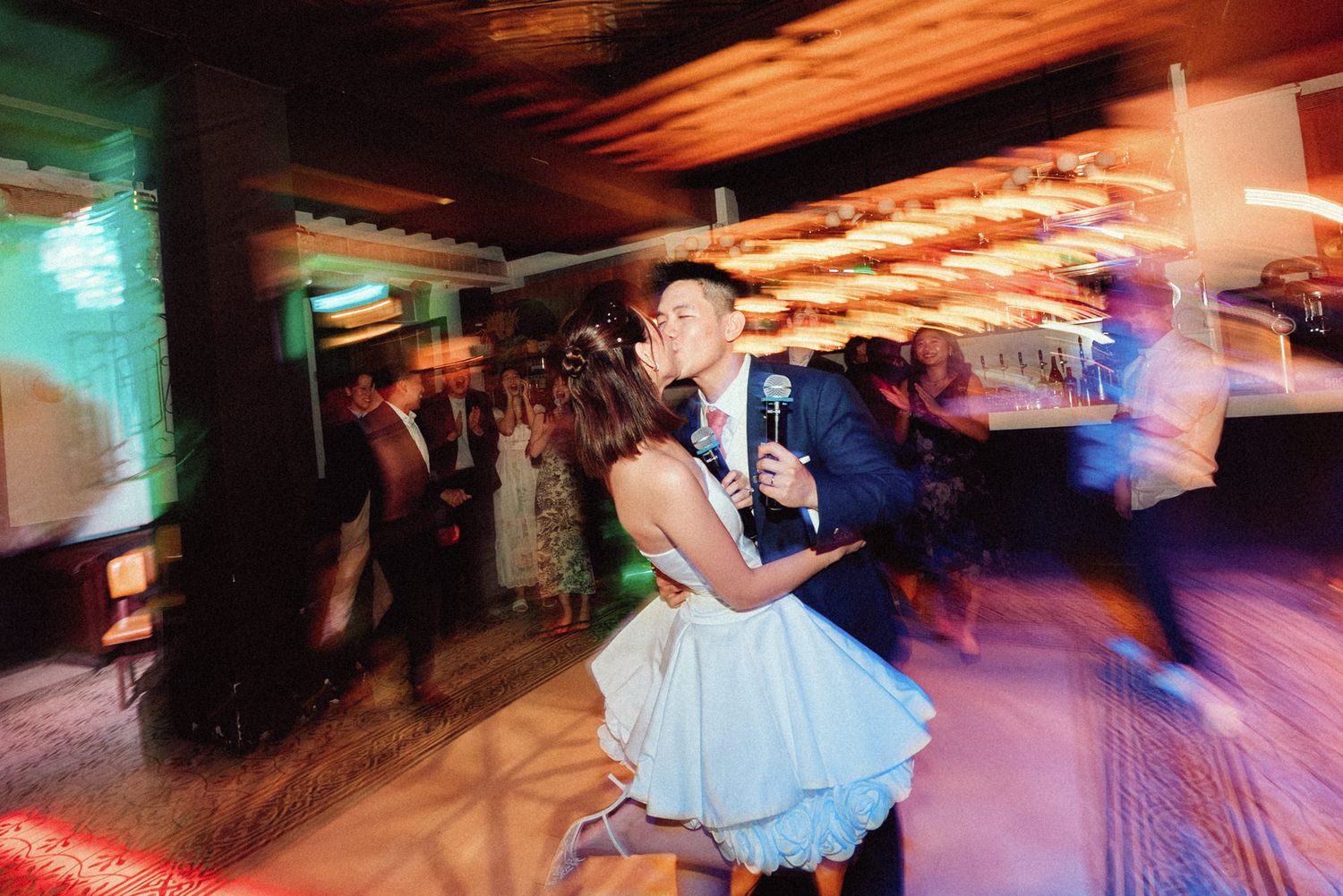 People dancing and enjoying themselves in a dimly lit nightclub with colorful lighting effects.