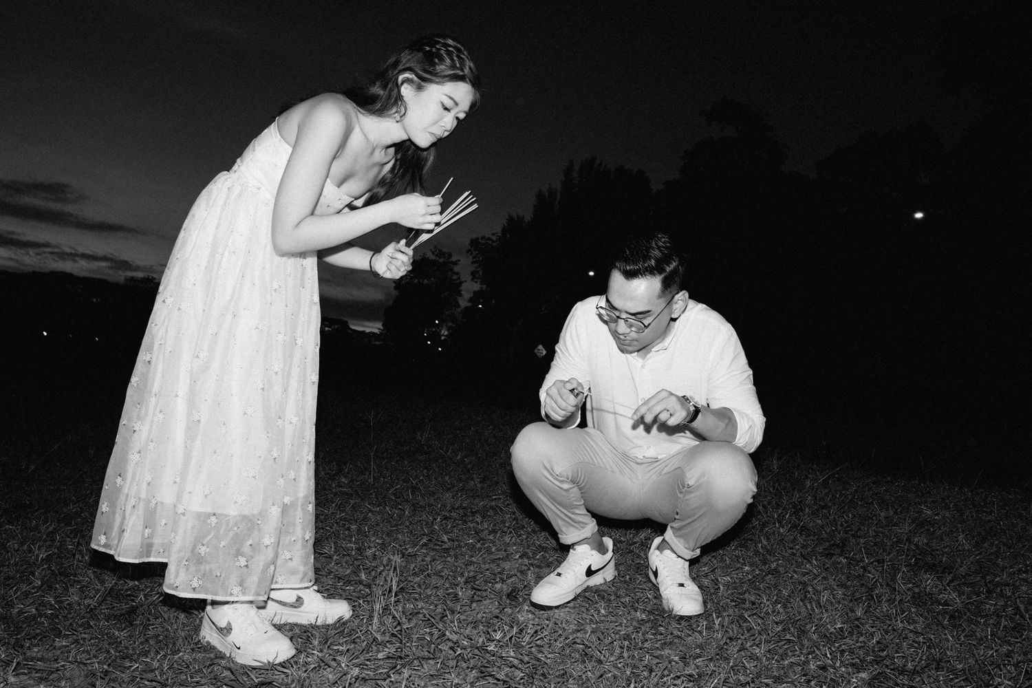 Black and white nighttime photo of people sitting on the ground.