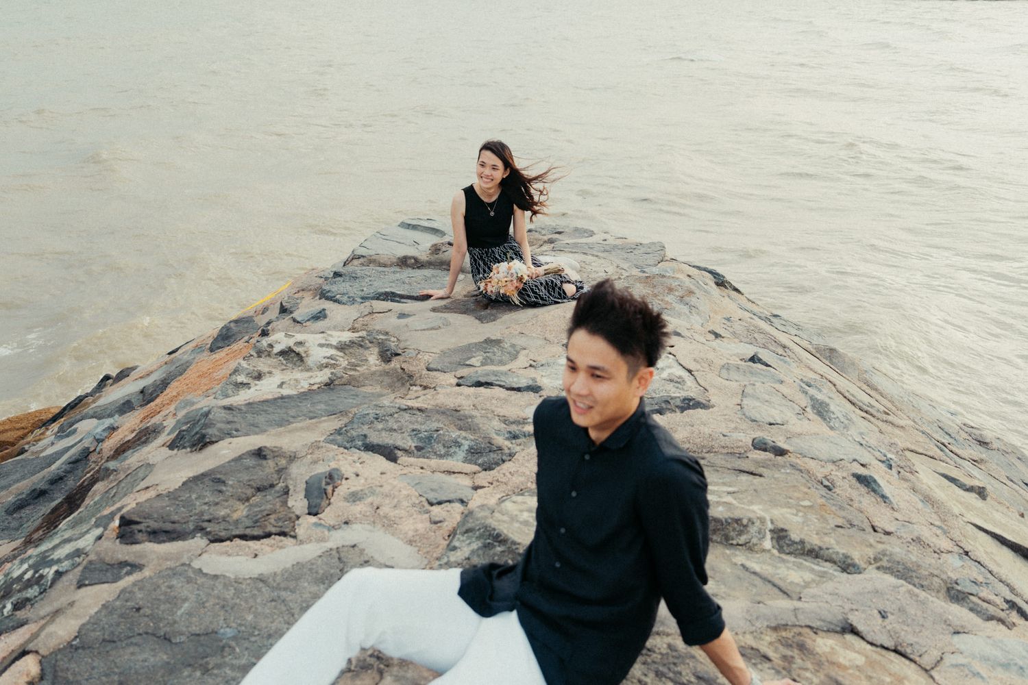 A couple explores rocky coastal formations along the shoreline.