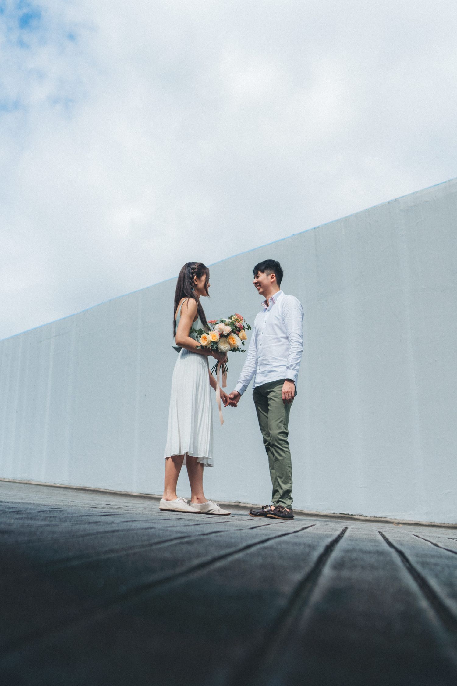 Two people in casual attire dance playfully together against a minimalist white wall backdrop in a sequence of photos.