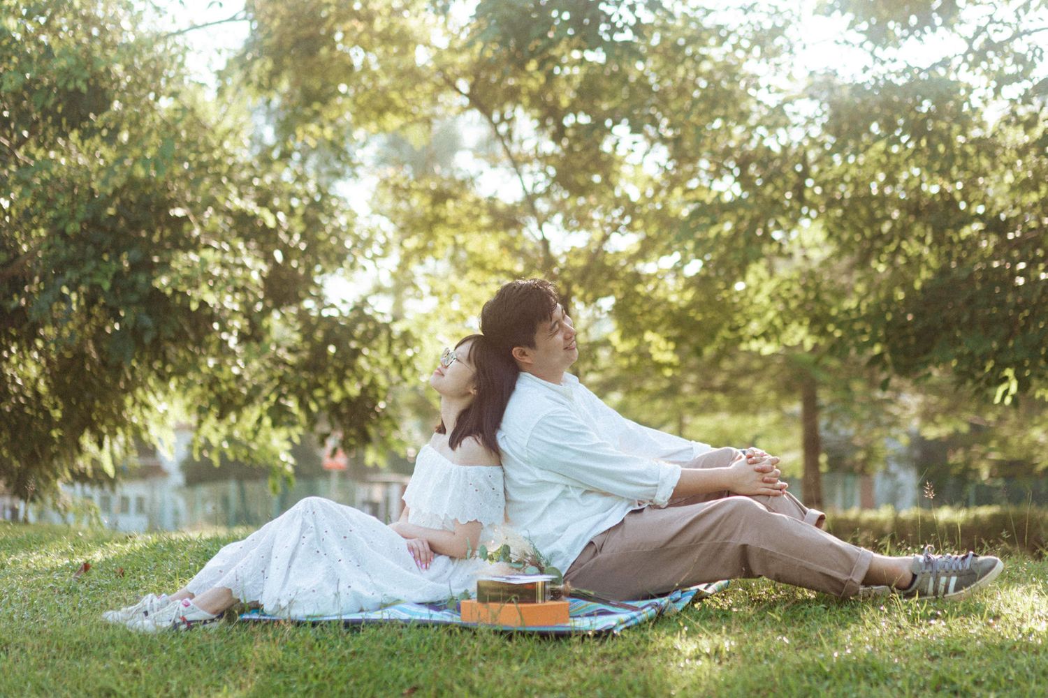People relaxing on blankets in a grassy outdoor area during a sunny afternoon.