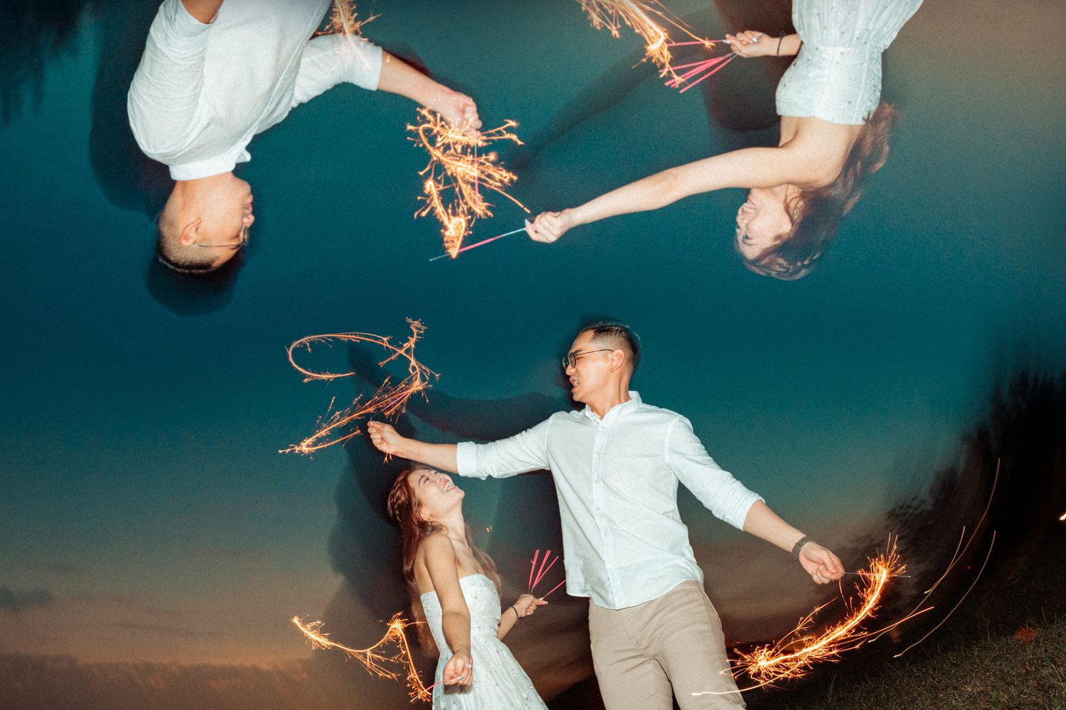 A couple dances together holding sparklers at dusk creating magical light trails in the air.