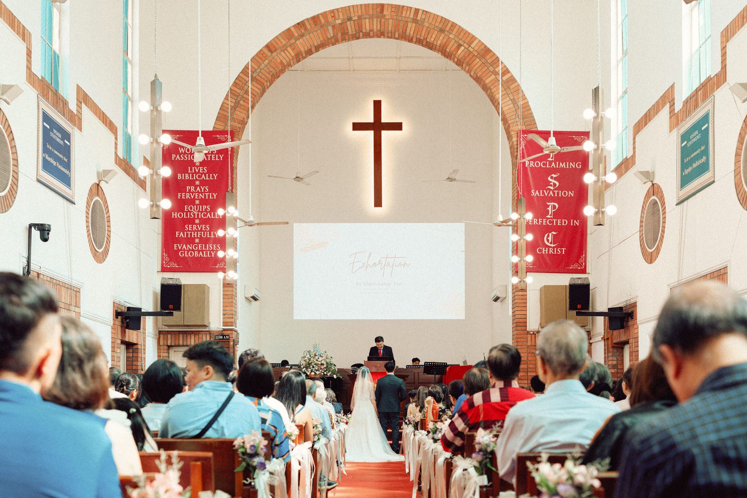 Church sanctuary with cross and red carpet during wedding celebration.
