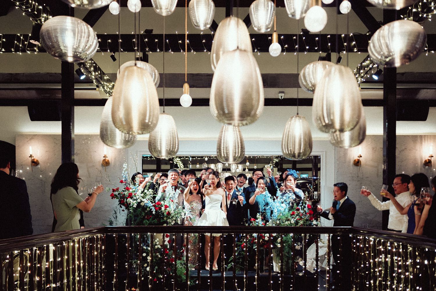 White paper lanterns illuminate a wedding reception venue with guests mingling beneath the decorative lighting.