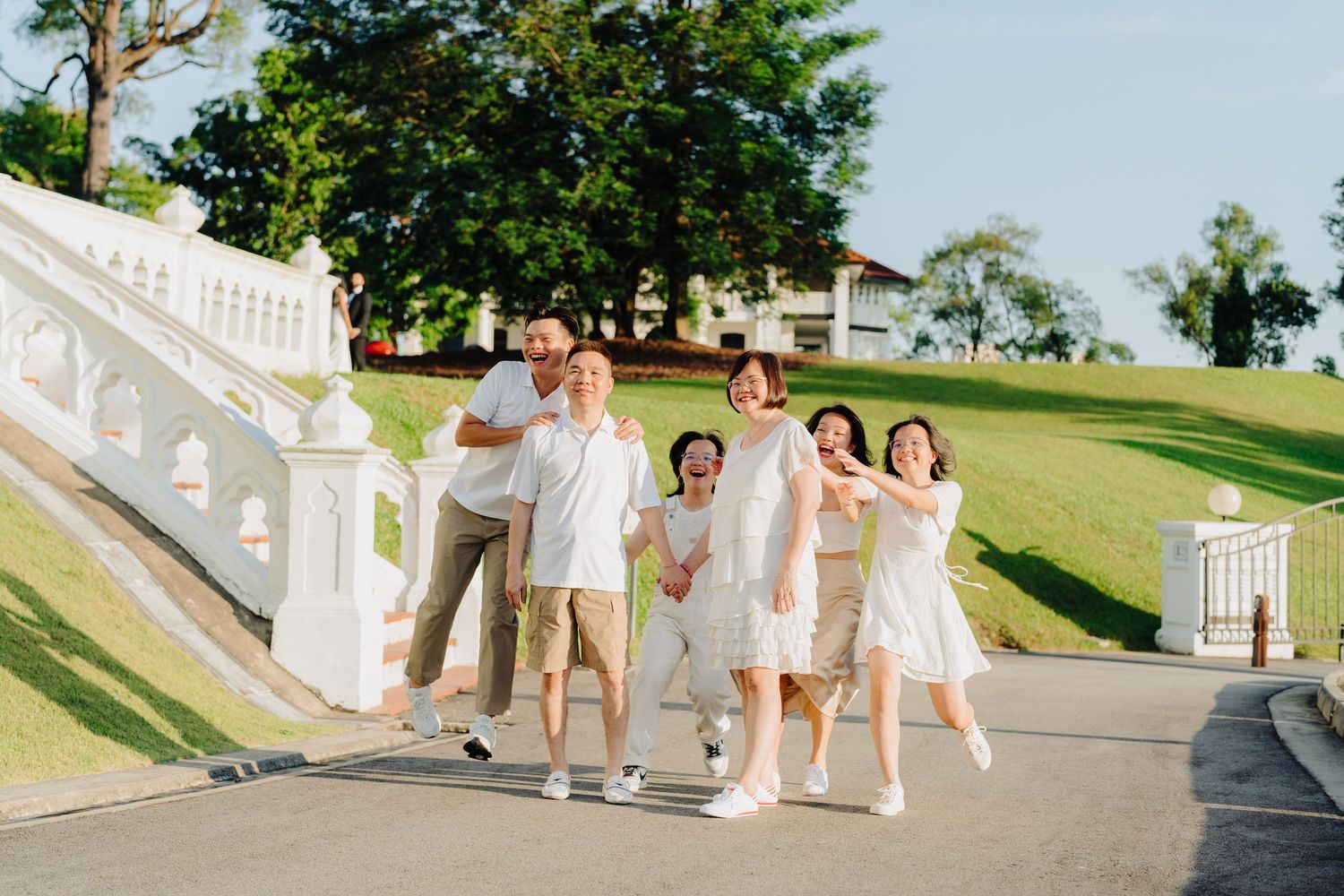 Group in white outfits walking together on a path at a tropical resort destination.