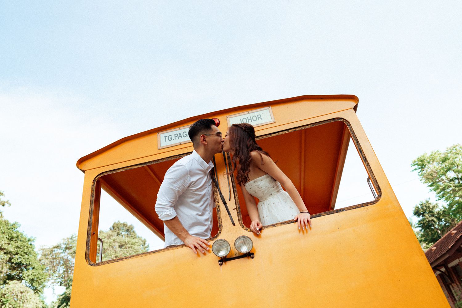 Orange vintage train car provides backdrop for outdoor photography session.