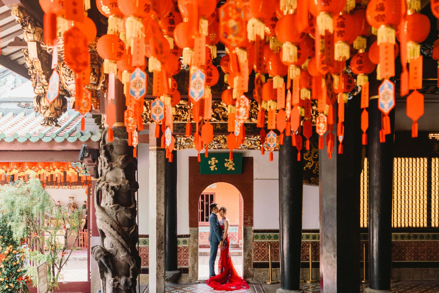 Red lanterns hanging in rows under traditional Chinese temple corridor.