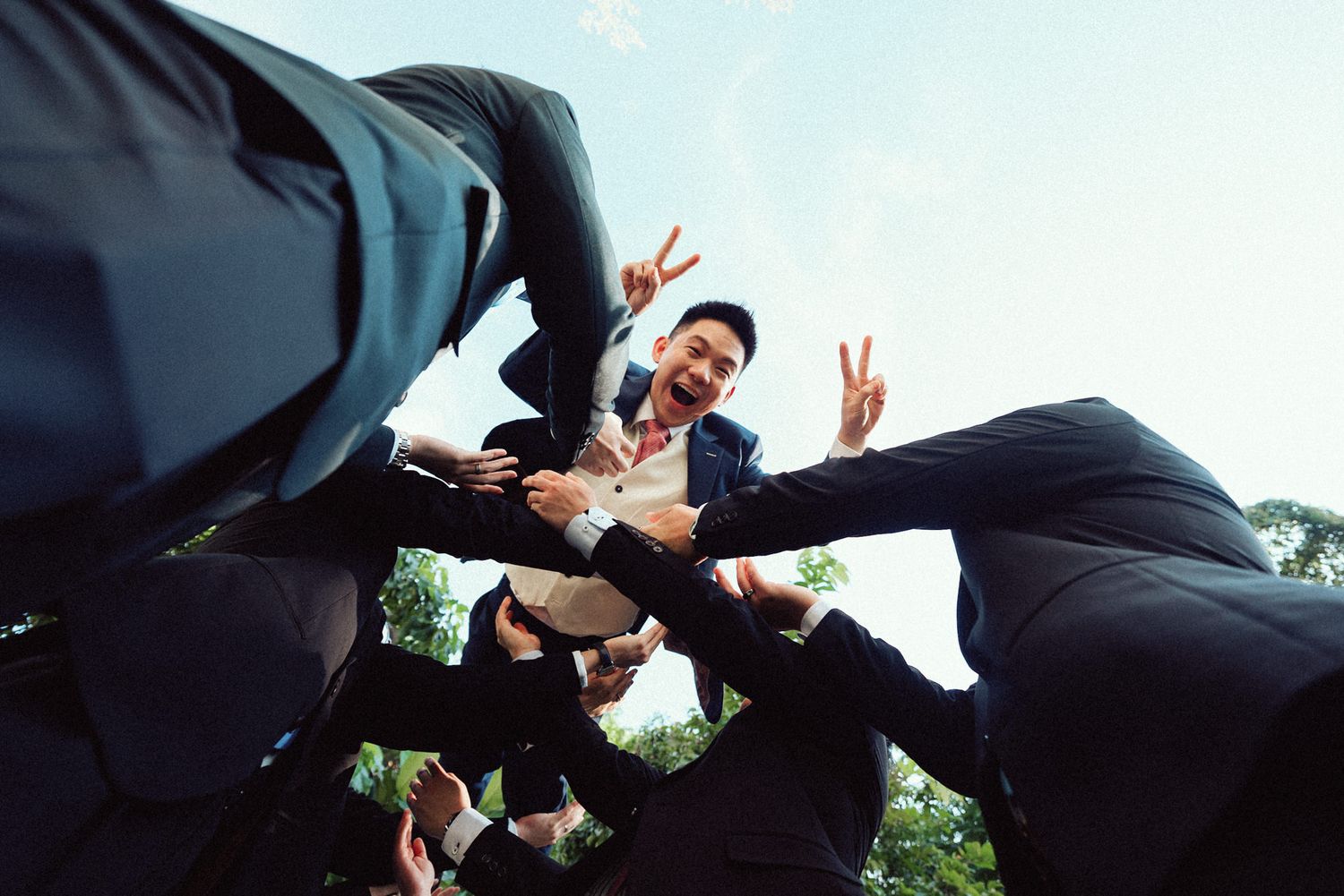 A series of low-angle shots showing people making peace signs against a bright sky background.