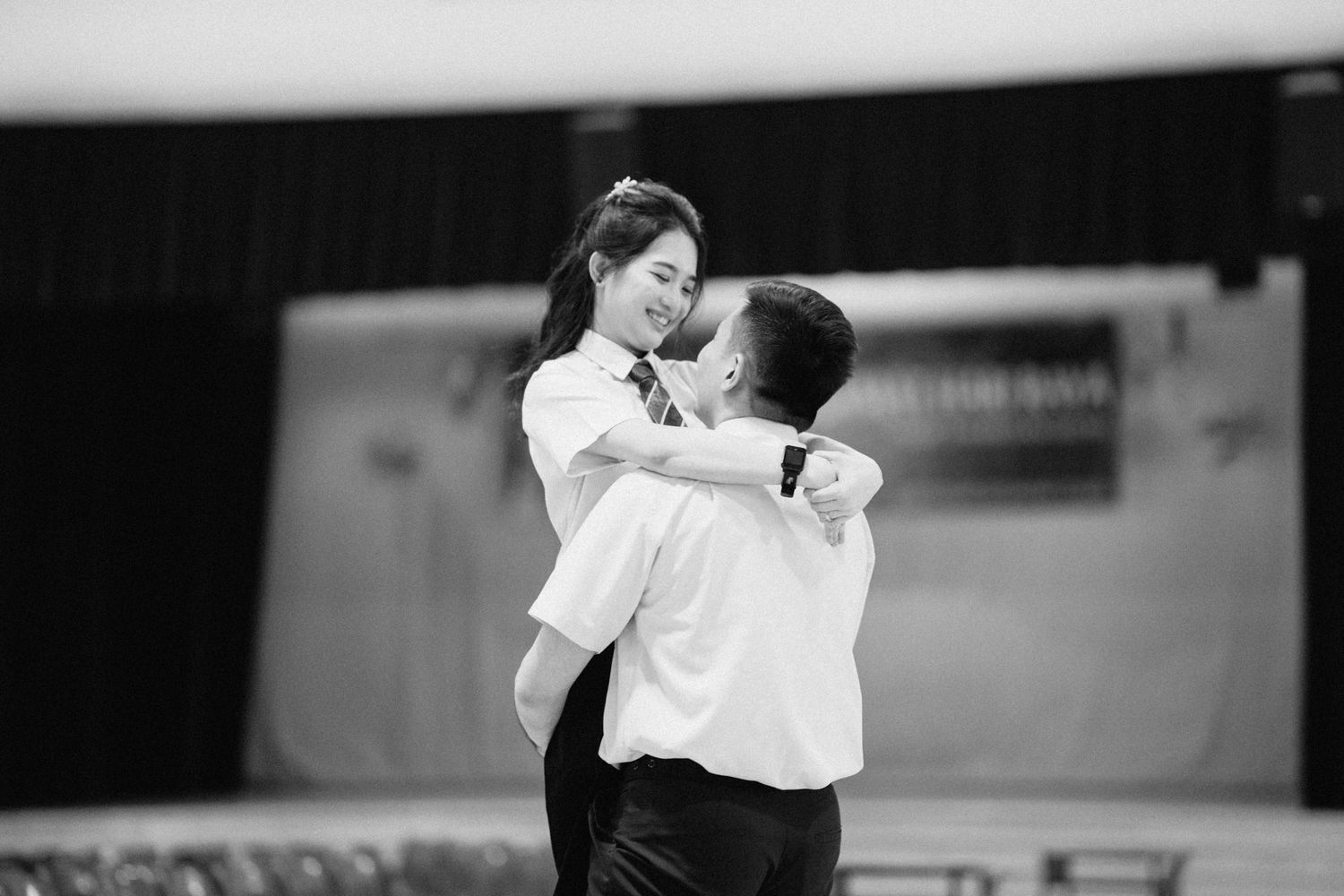 A black and white photo of a couple dancing together in an indoor space.