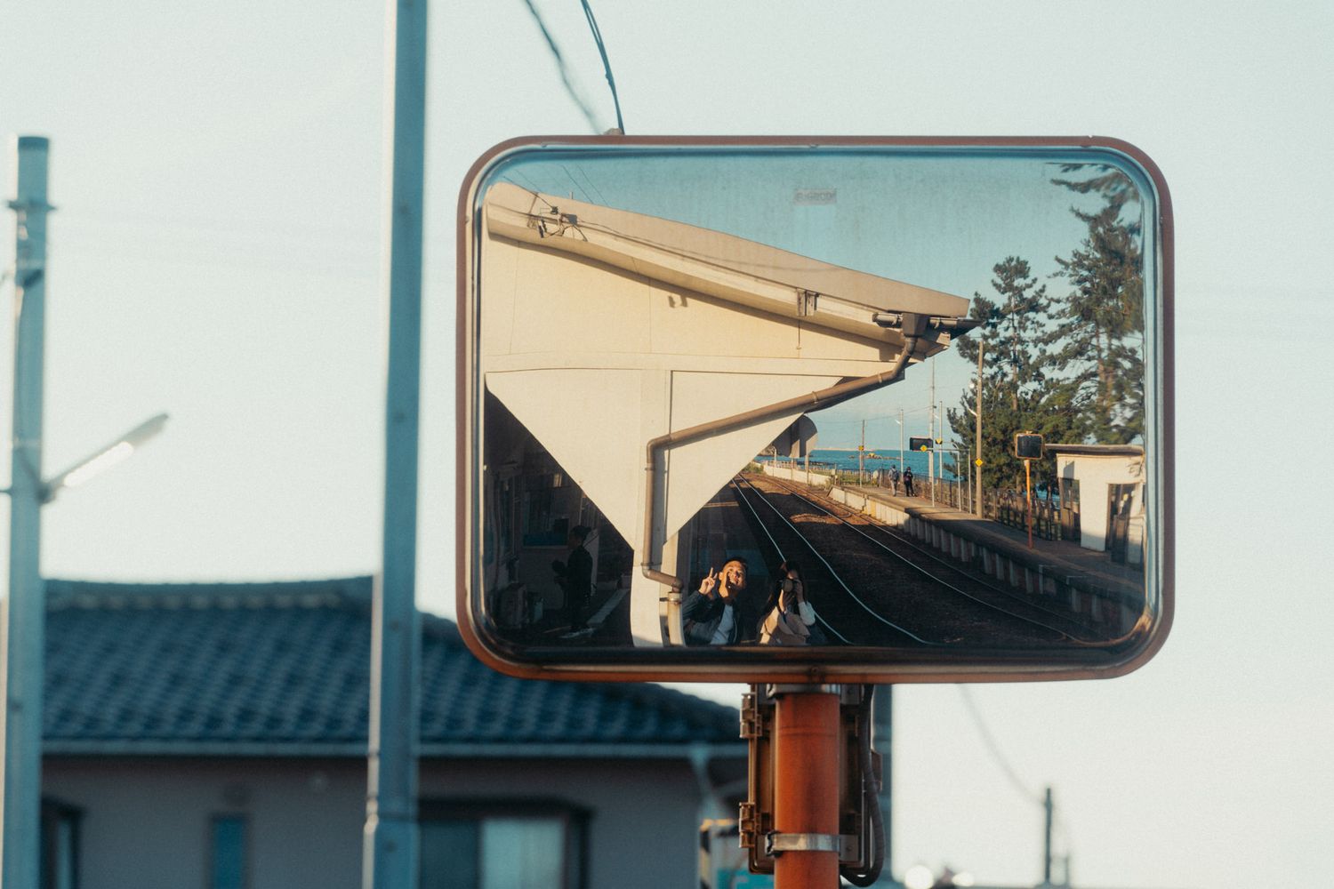 View through a train window showing side mirrors and railway infrastructure.