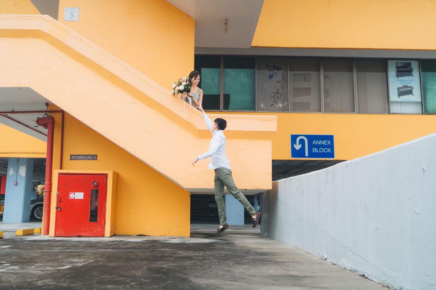 Person climbing orange staircase in modern building with geometric architectural elements and turquoise accents.