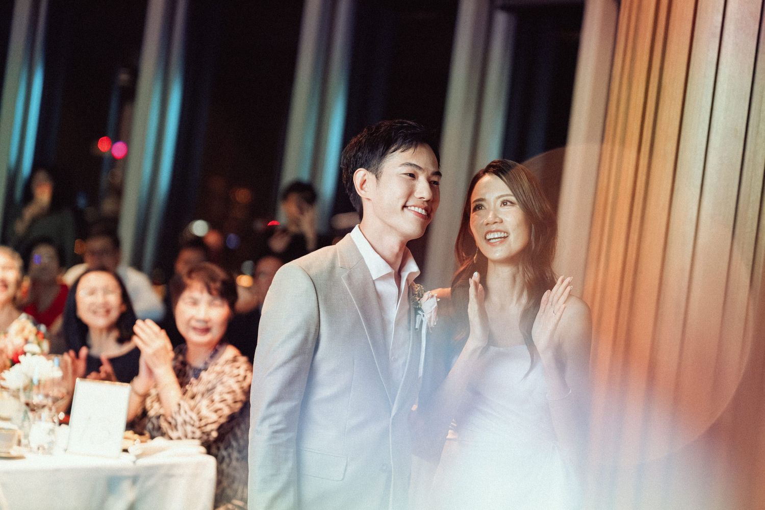 Couple sharing a moment together during their wedding reception with guests in background.