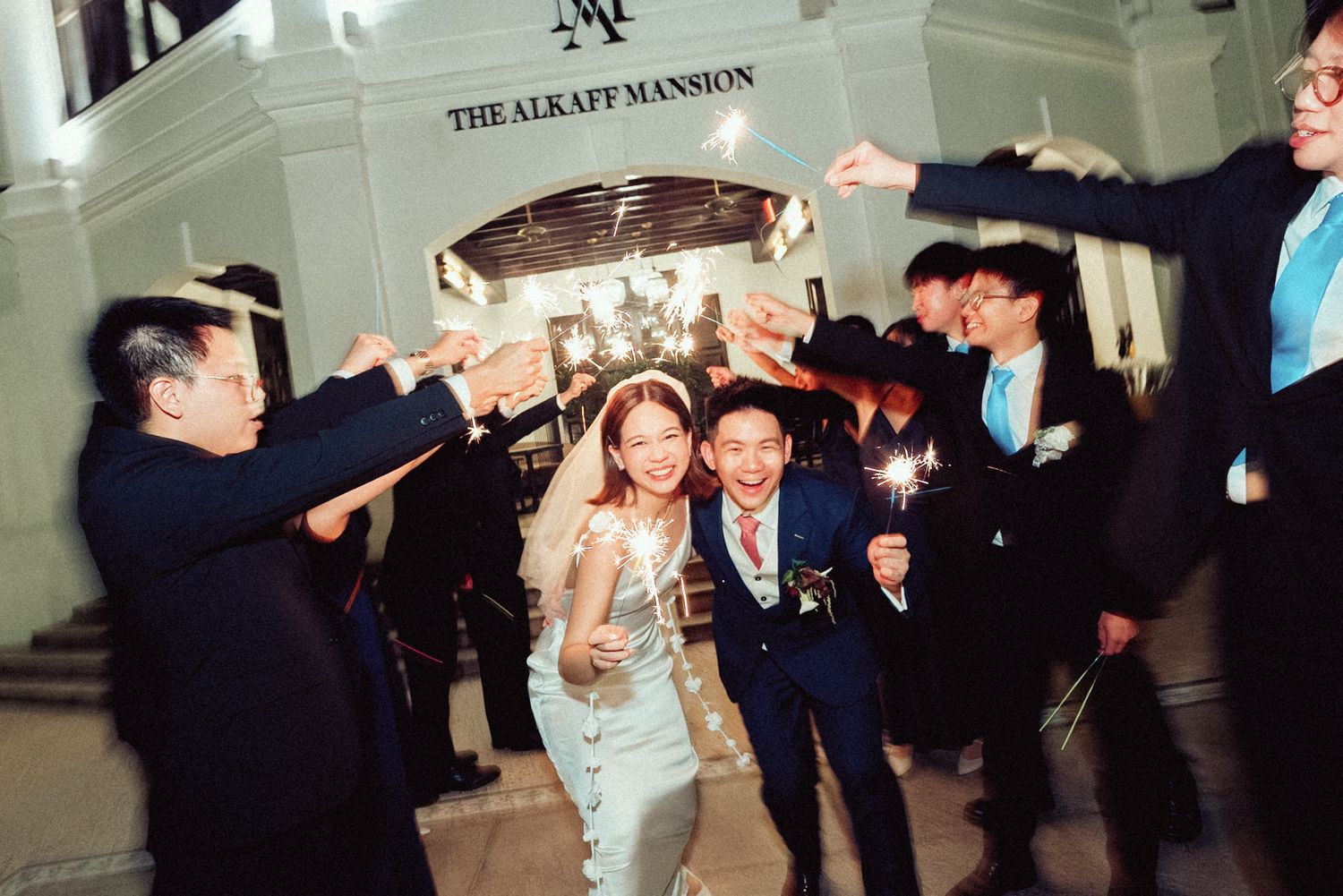 A lively wedding reception dance floor filled with guests celebrating and dancing under elegant lighting.