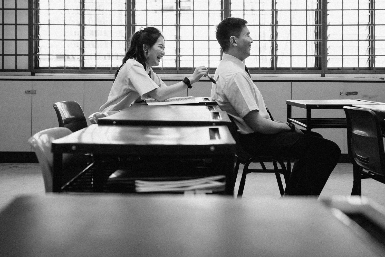 Black and white photo of students studying in a classroom with large windows.