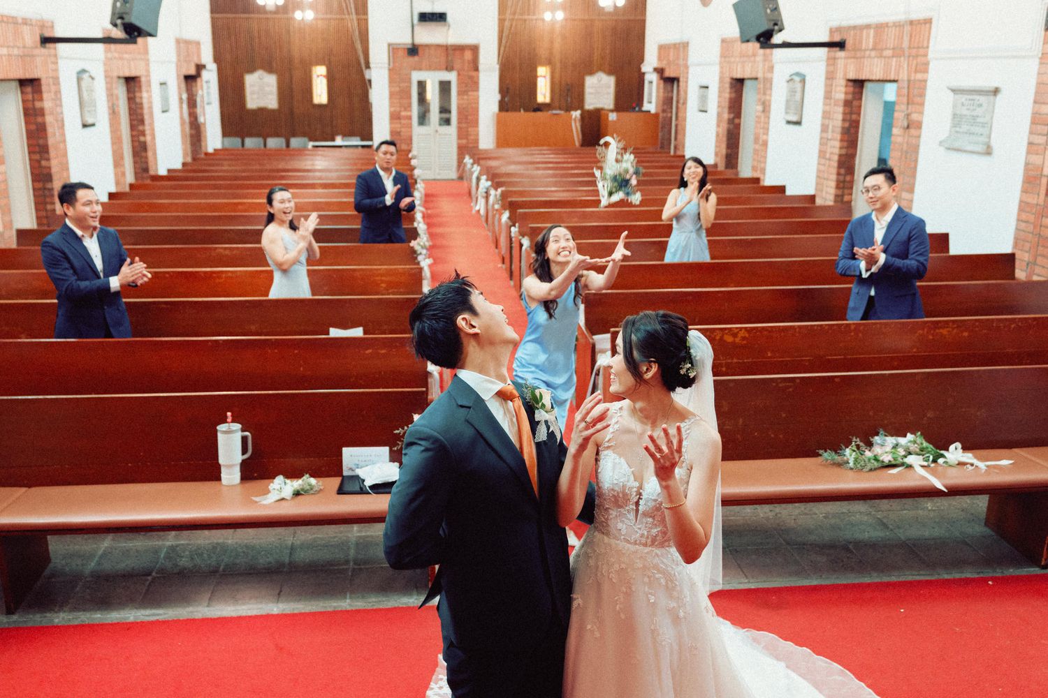 Church sanctuary with red carpeted aisle and wooden pews during wedding ceremony.