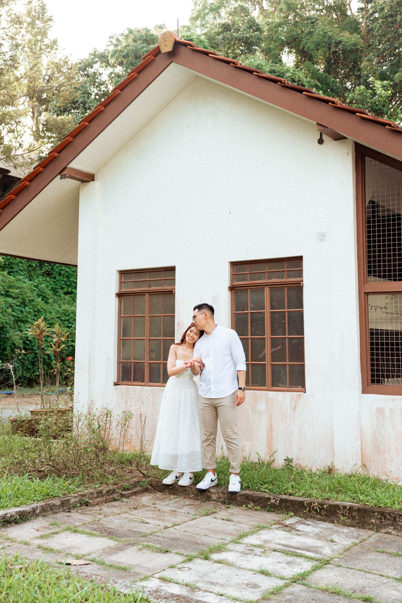 A white building with brown windows and metal gates serves as a backdrop for a photo session.