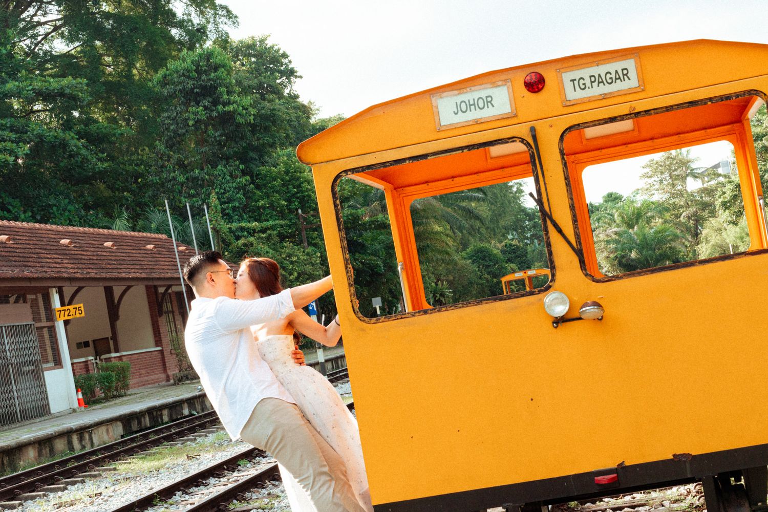 Orange vintage train car provides backdrop for outdoor photo session.