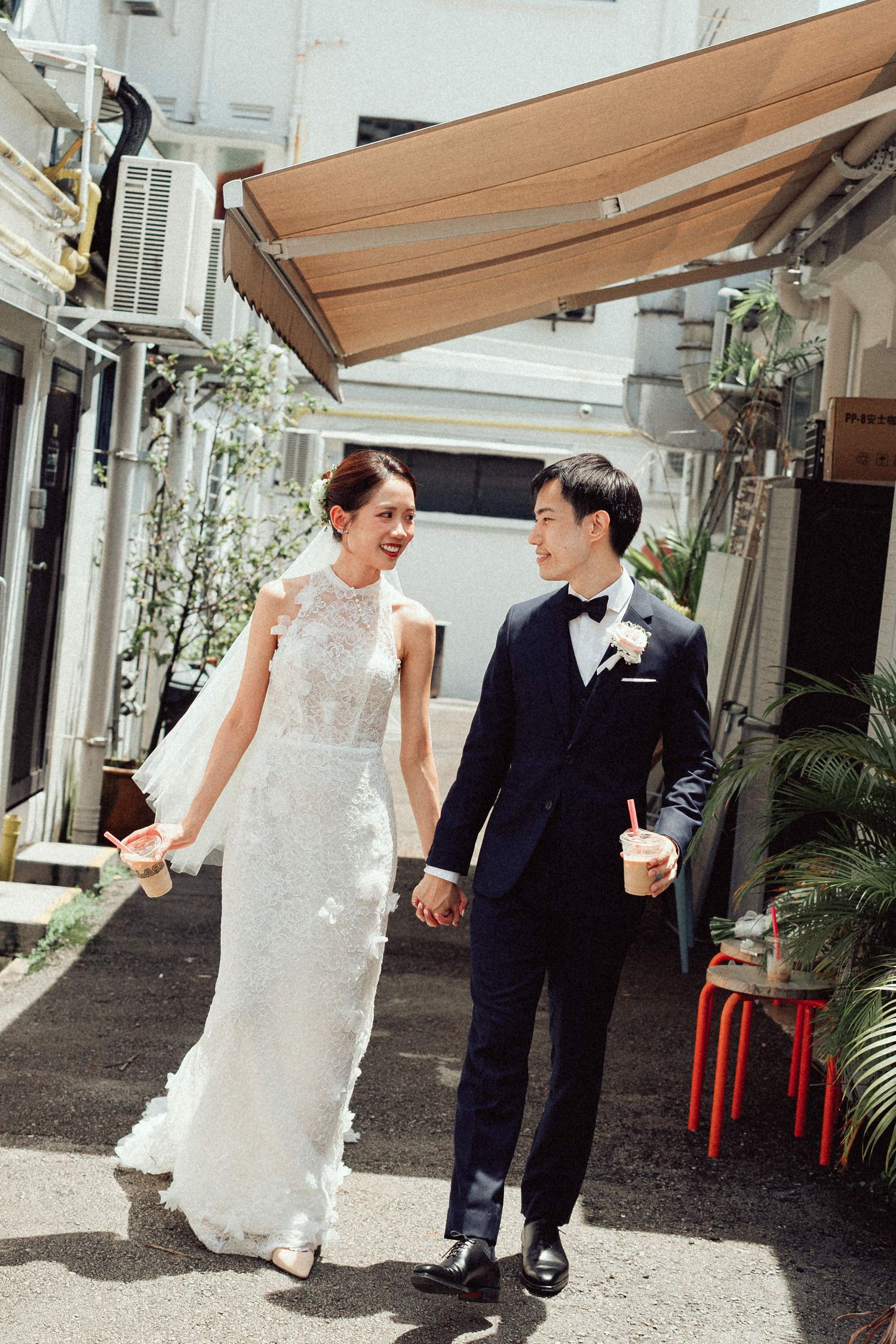 Newlyweds share playful moments while walking along an outdoor shopping area.