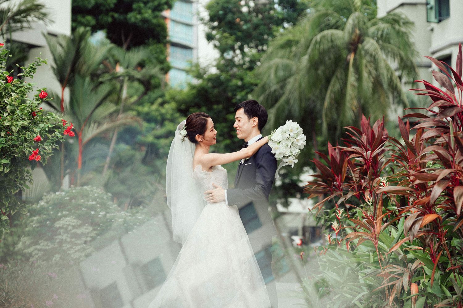Tropical garden wedding setting with palm trees and red flowers in the background.