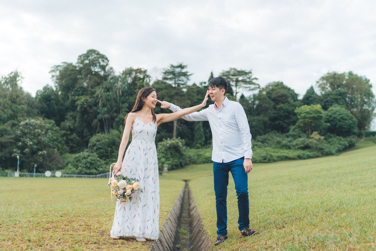 A couple holds hands while walking through a lush green meadow on a sunny summer day.