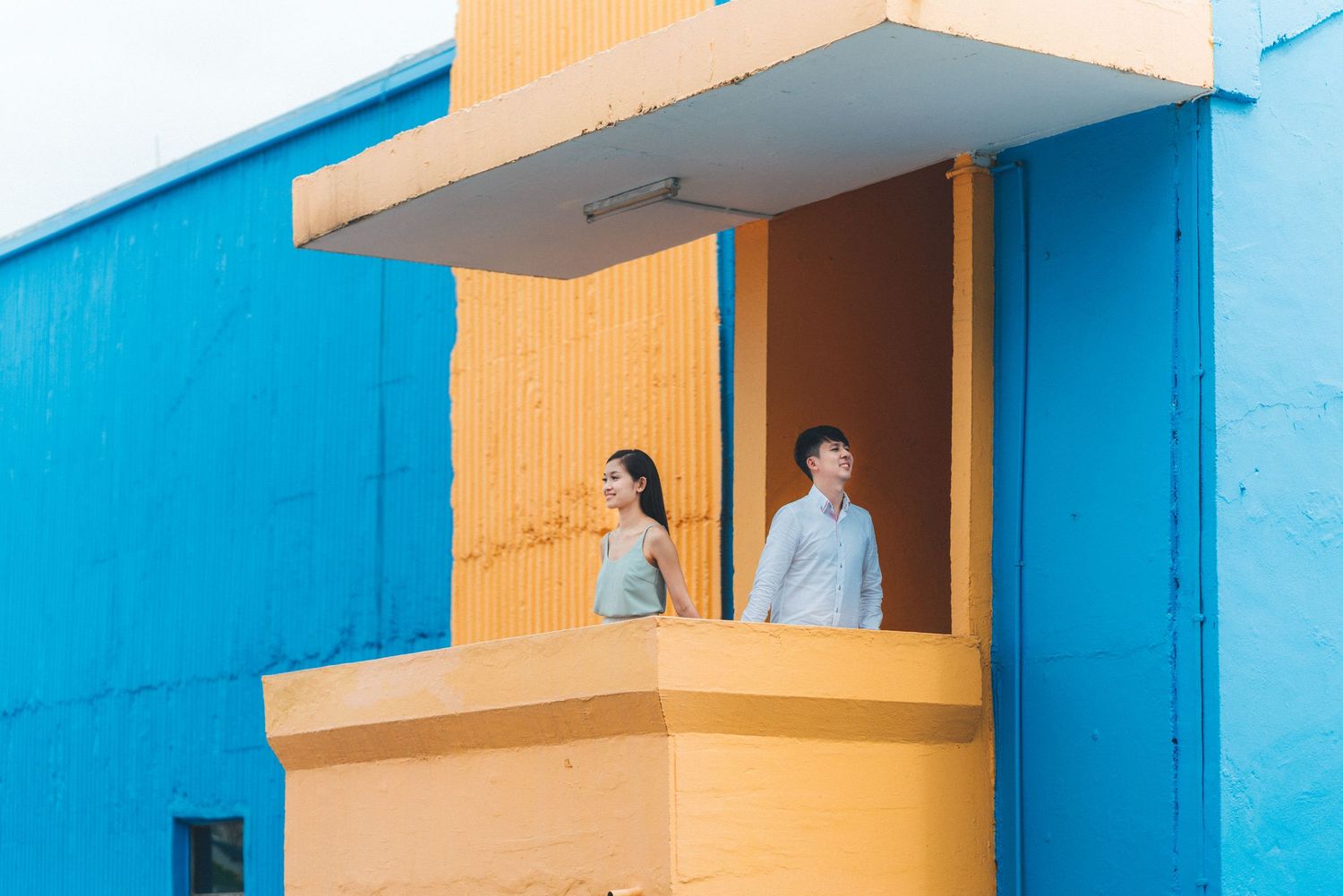 Modern apartment building exterior with bright blue and orange color scheme features geometric balconies and railings.